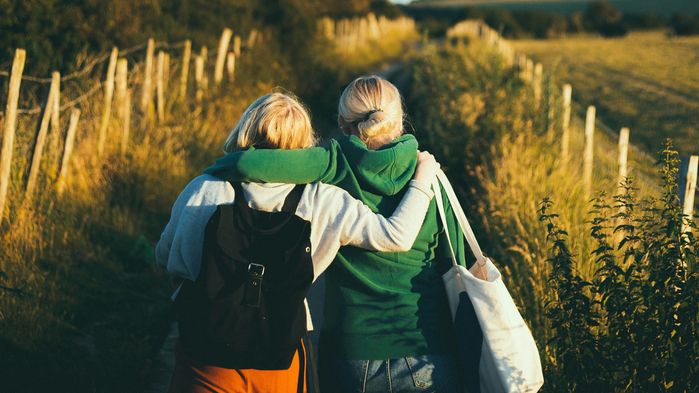 Två unga tjejer som går på en grusväg.