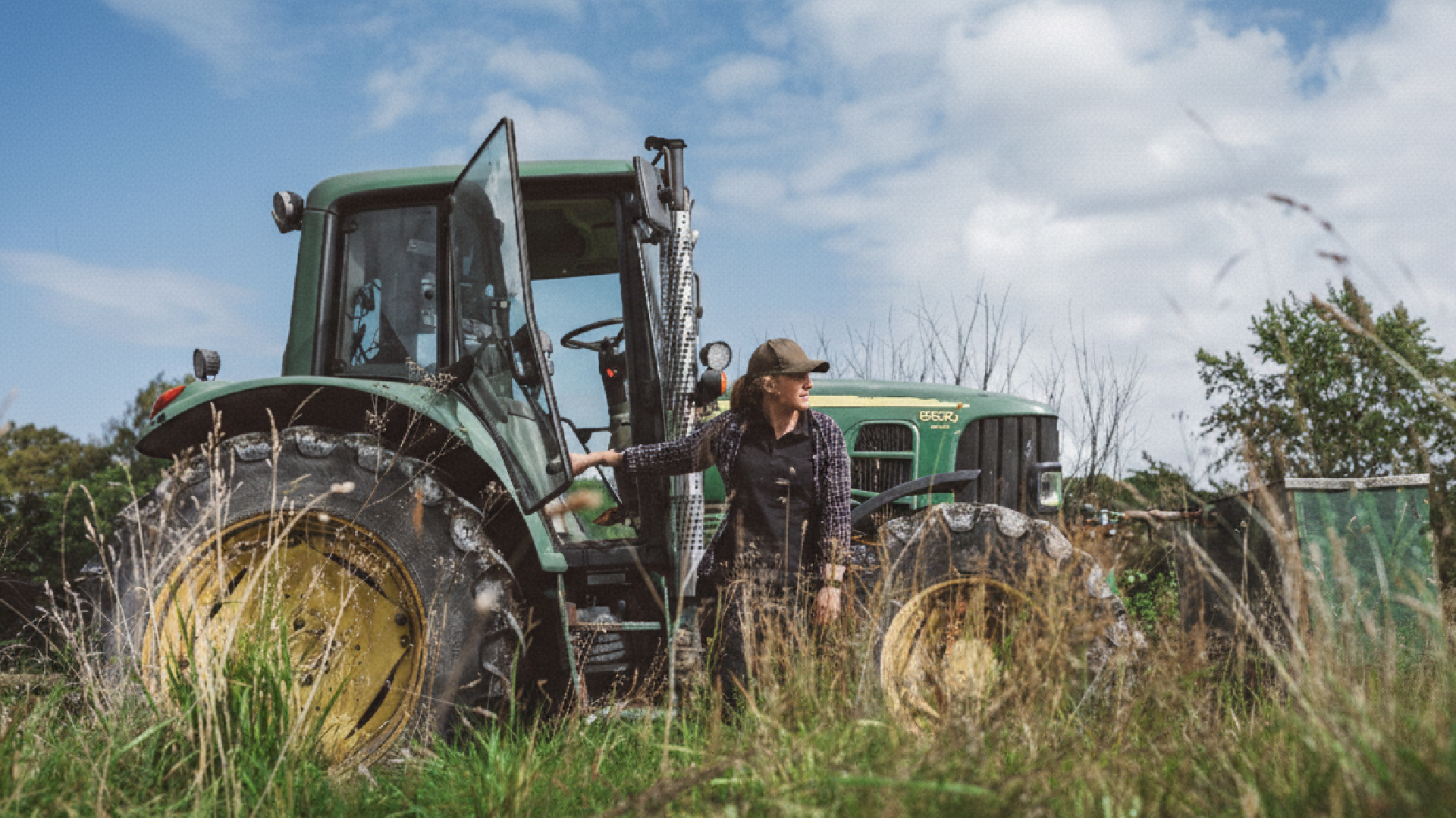 Kvinna med traktor i högt gräs