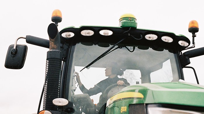 Kvinna i en förarhytt i en traktor