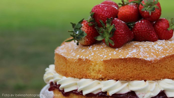 En sommartårta i närbild, den är gjort på sockerkaka och grädde och det är färska jordgubbar på toppen.